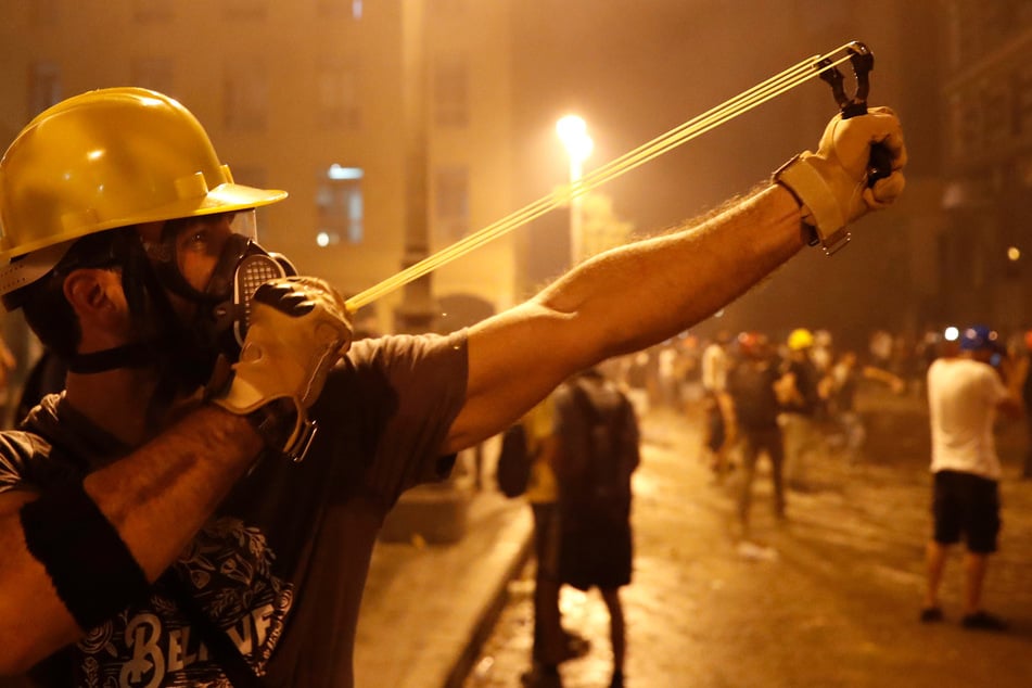 Ein Protestierender schleudert mit einer Schleuder gegen die libanesische Bereitschaftspolizei, während eines regierungskritischen Protests.