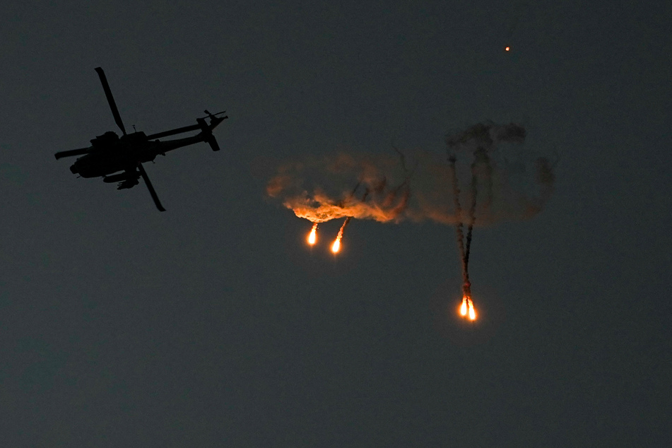 Ein israelischer Apache-Hubschrauber feuert vom Süden Israels aus gesehen Leuchtraketen über dem Gazastreifen ab.