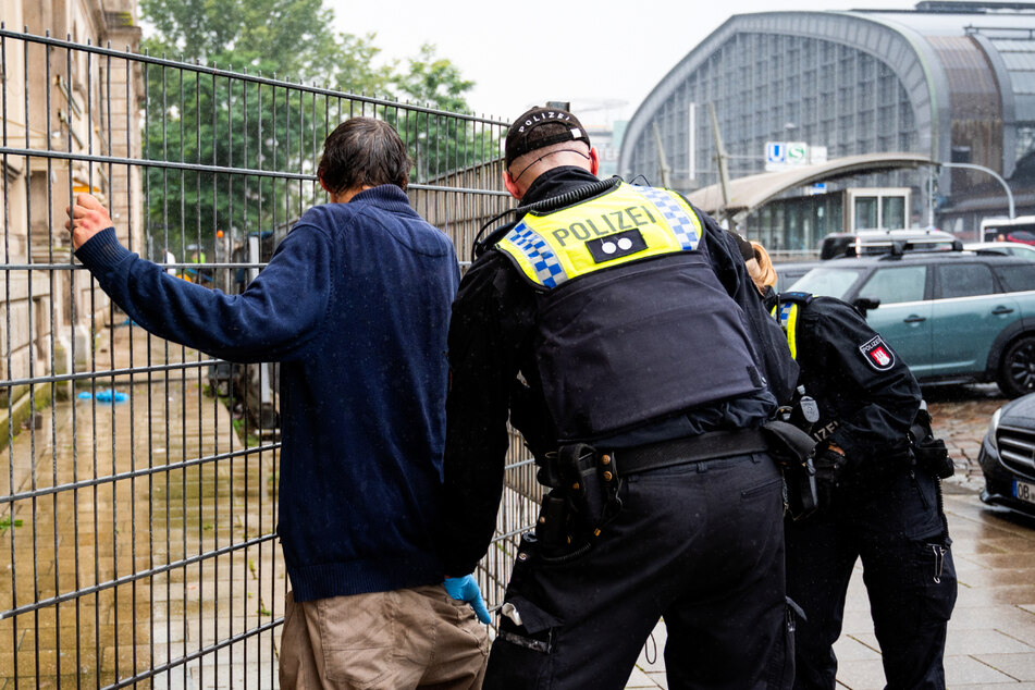 Polizisten kontrollieren einen Mann auf einem Vorplatz vom Hauptbahnhof. Sie sollen Drogen bei ihm gefunden haben.