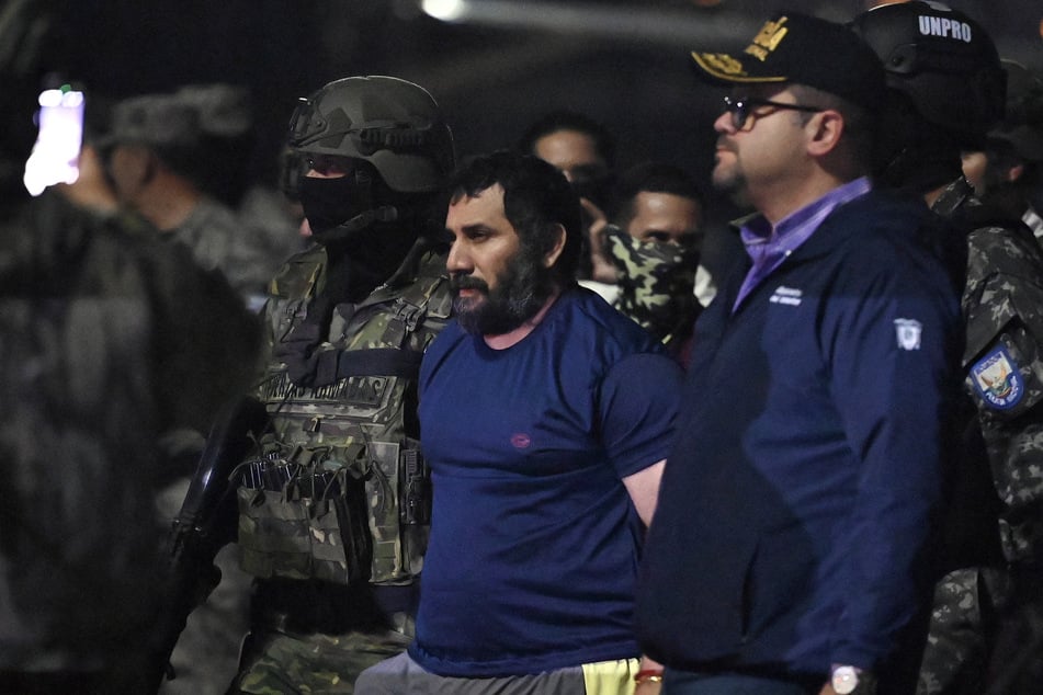 Drug trafficker Adolfo Macias, alias Fito, is guarded by Ecuador's Interior Minister John Reimberg (r.) and military personnel upon arrival at the air base in Guayaquil on June 25, 2025.