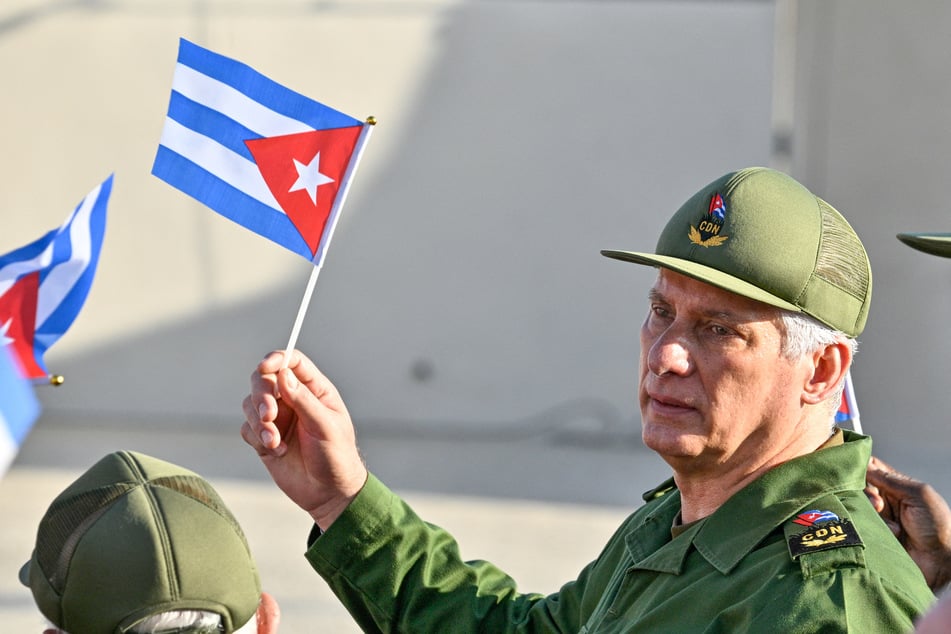 President Miguel Diaz-Canel holds a Cuban flag during a rally in support of former president Raul Castro, after his indictment, outside the US Embassy in Havana on May 22, 2026.