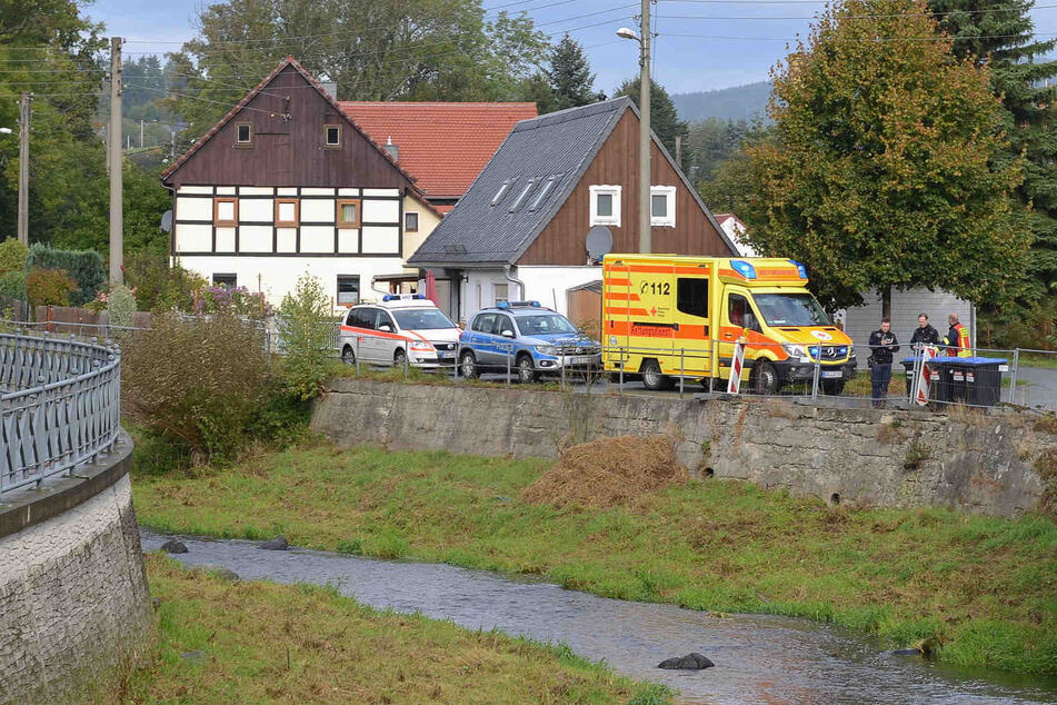 Polizei und Rettungsdienst stehen am Rand der Mandau. Dort hatte eine Passantin eine Frau aus dem Wasser gerettet.