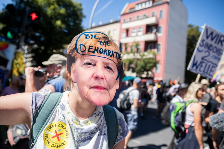 Eine Frau trägt eine Merkel-Maske mit der Aufschrift "Bye bye Demokratie" auf der Demonstration gegen die Corona-Beschränkungen.