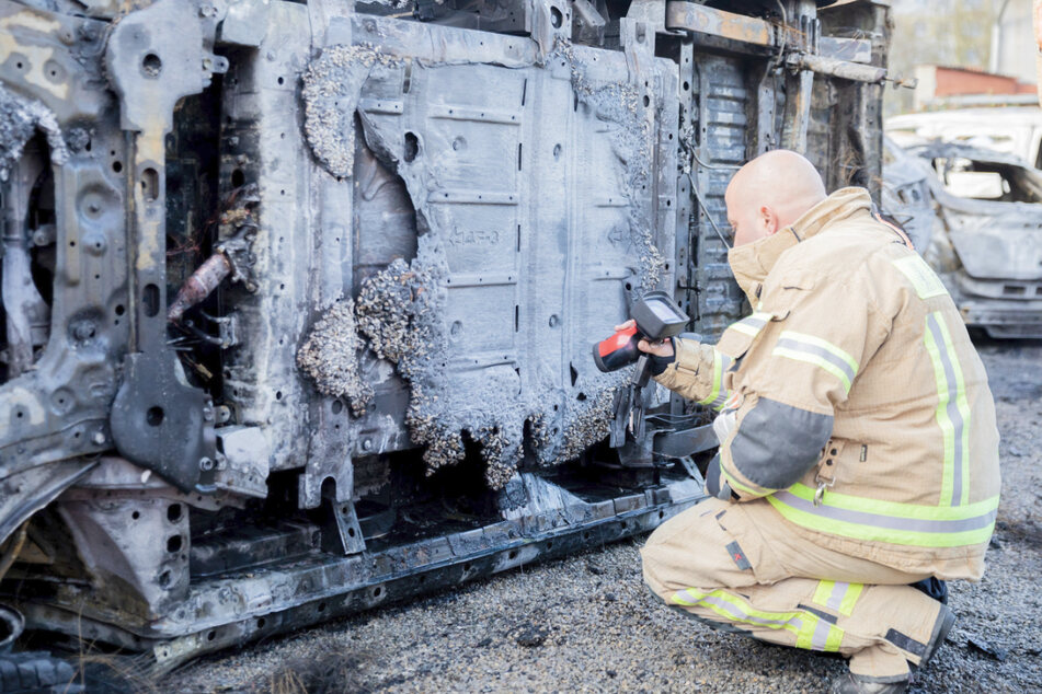 Ein Feuerwehrmann misst mit einer Wärmebildkamera die Temperatur des Akkus.
