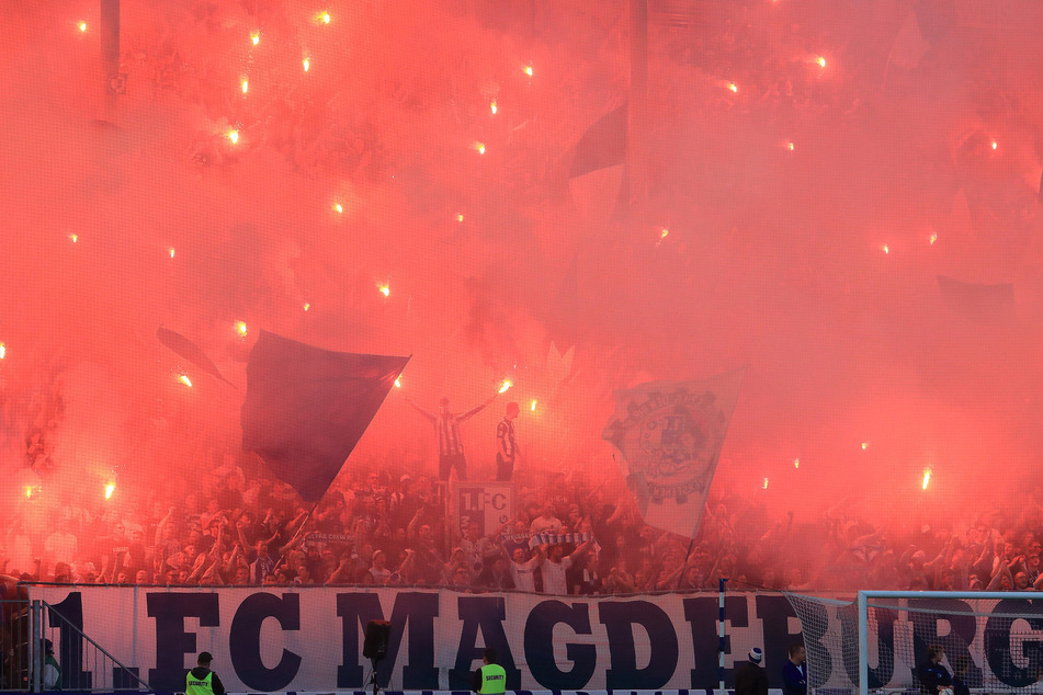 Anhänger des 1. FC Magdeburg feiern vor einem Spiel im eigenen Stadion mit Bengalos.