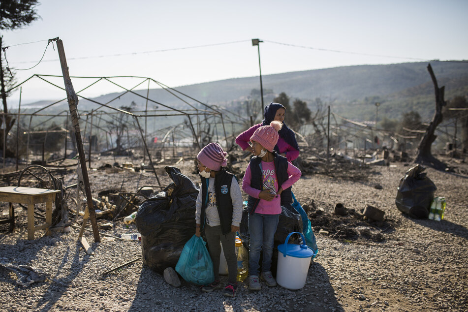 Eine Familie steht innerhalb des ausgebrannten Flüchtlingslagers Moria.