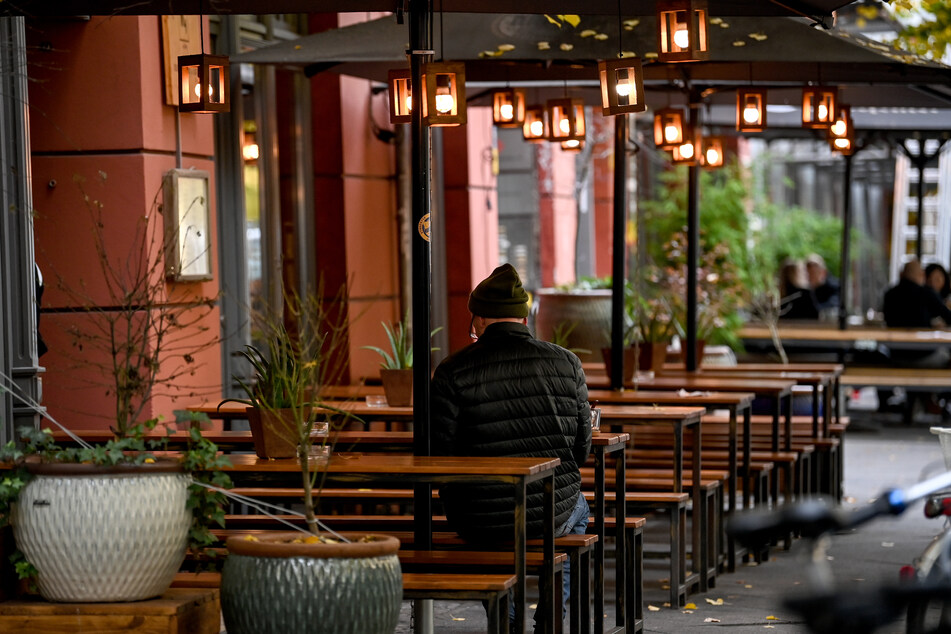 Ein Mann sitzt im Außenbereich eines Restaurants in Berlin.