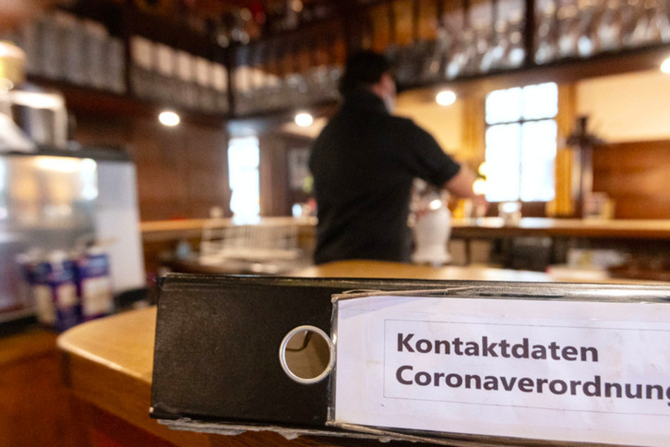 Ein Ordner mit der Aufschrift "Kontaktdaten Coronaverordnung" liegt in einer Gaststätte auf der Theke.