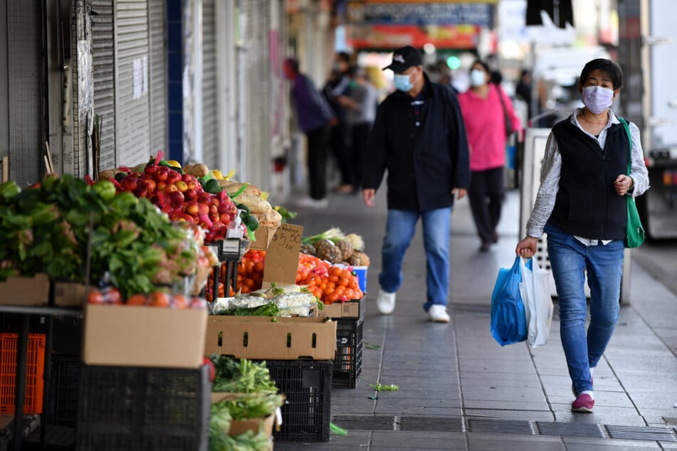 Kunden mit Gesichtsmasken gehen die Beamish Street in Campsie in Sydney entlang.