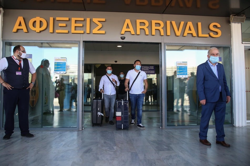 Touristen mit medizinischem Mundschutz kommen am internationalen Flughafen der griechischen Insel Kreta an.