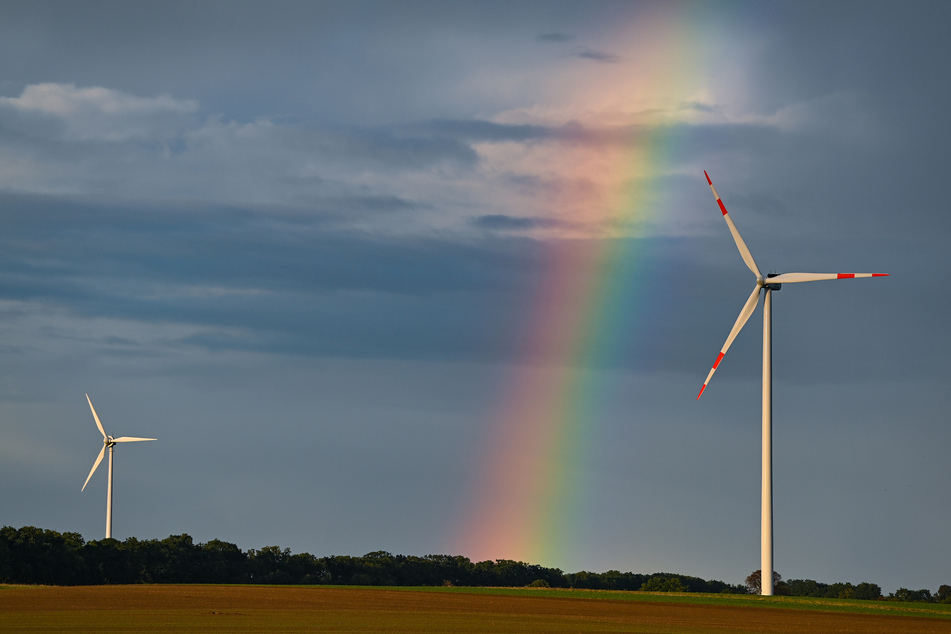 Ein Regenbogen spannt sich über die Landschaft mit zwei Windenergieanlagen im Windpark "Odervorland" im Landkreis Oder-Spree.