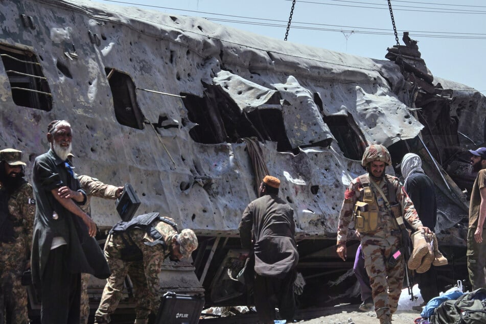 Sicherheitsbeamte untersuchen einen beschädigten Zugwaggon auf einem Bahngleis am Ort einer Bombenexplosion in Quetta.
