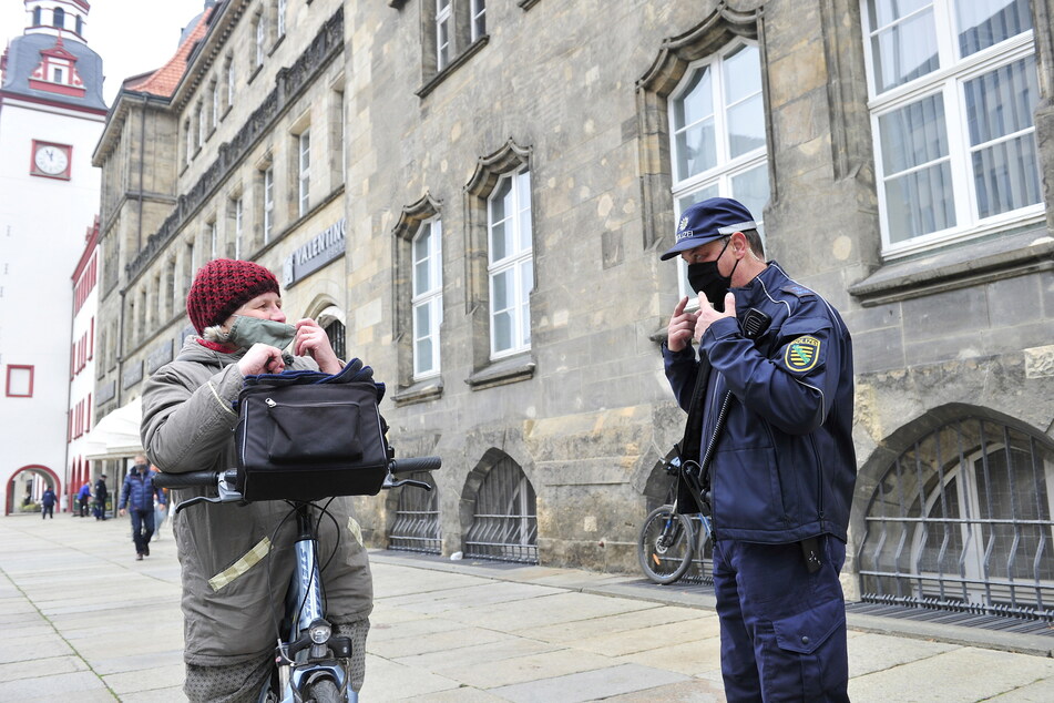 Ein Fingerzeig von Polizeihauptmeister Frank Strachotta (52) auf die eigene Maske reicht, um Ulrike Fedke (56) an die Maske zu erinnern.