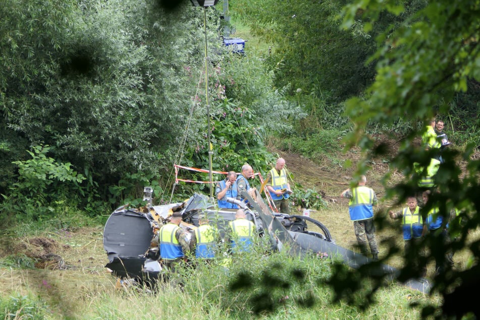 Flugunfallermittler der Bundeswehr untersuchen am Ufer das Helikopterwrack.