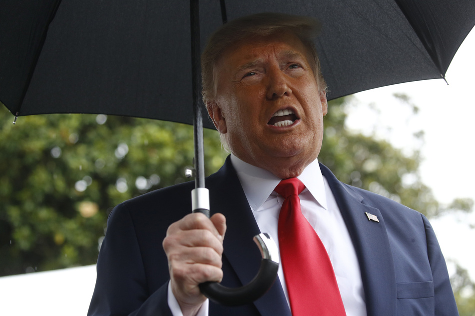 Donald Trump, Präsident der USA, hält einen Regenschirm und spricht auf dem Südrasen des Weißen Hauses mit Journalisten.