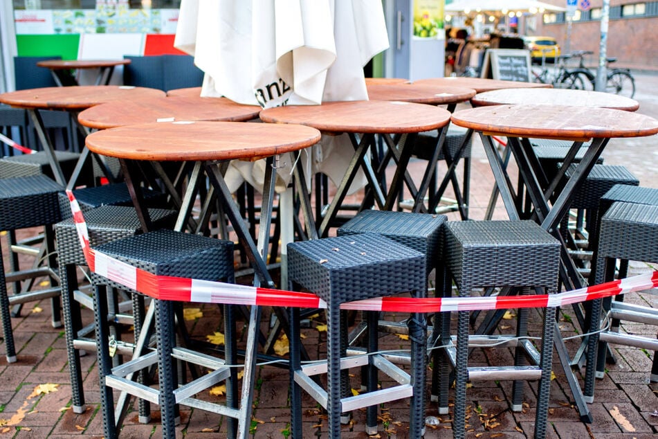 Tische und Stühle stehen vor einer Pizzeria, die derzeit nur Speisen zum Mitnehmen anbieten kann.