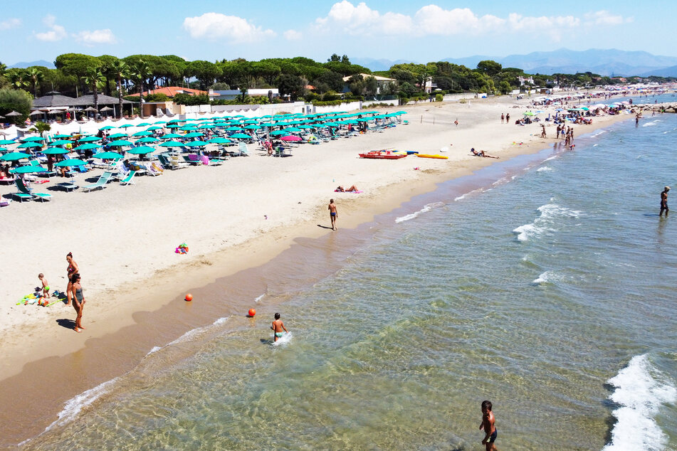 Einige Besucher baden im Meer am italienischen Strand.