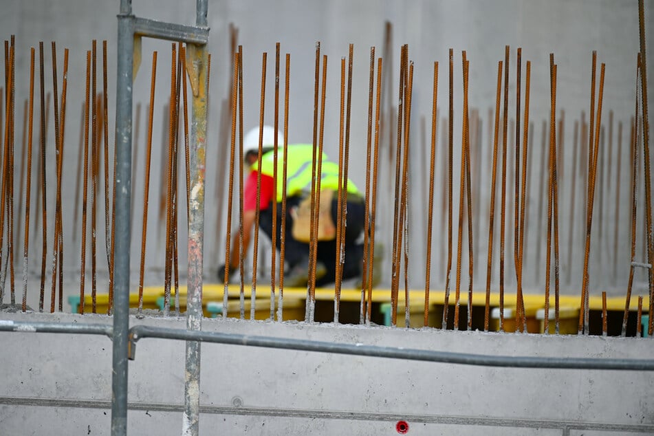Ein Handwerker arbeitet auf einer Baustelle an Betonstahlträgern. (Symbolbild)