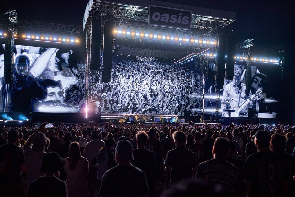 Liam Gallagher and Noel Gallagher of Oasis are shown on video screens as they perform during their reunion tour in Toronto, Canada, on August 24, 2025.