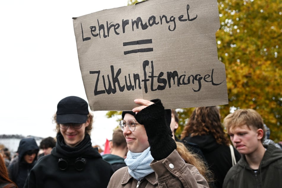 Teilnehmer der "Gen Z regelt"-Demo in Frankfurt halten ein Plakat mit der Aufschrift "Lehrermangel = Zukunftsmangel" in die Höhe.