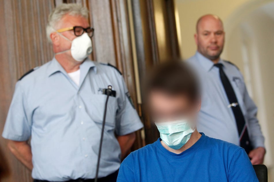 Der Angeklagte und zwei Justizbeamte vor dem Prozessbeginn in Moers (Archivbild).