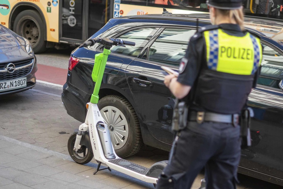 Eine Polizistin nimmt den Unfall zwischen einem E-Scooter-Fahrer und einem Fußgänger auf.