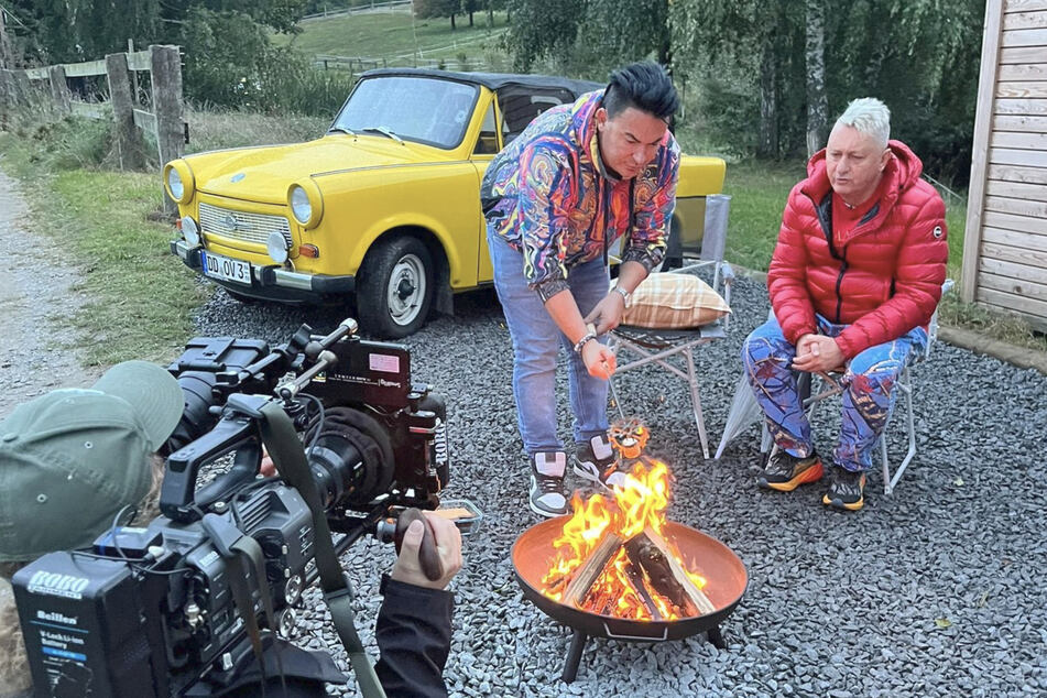 Matthias Mangiapane und sein Ehemann Hubert Fella legen für den Dreh eine Rast am warmen Feuer ein.