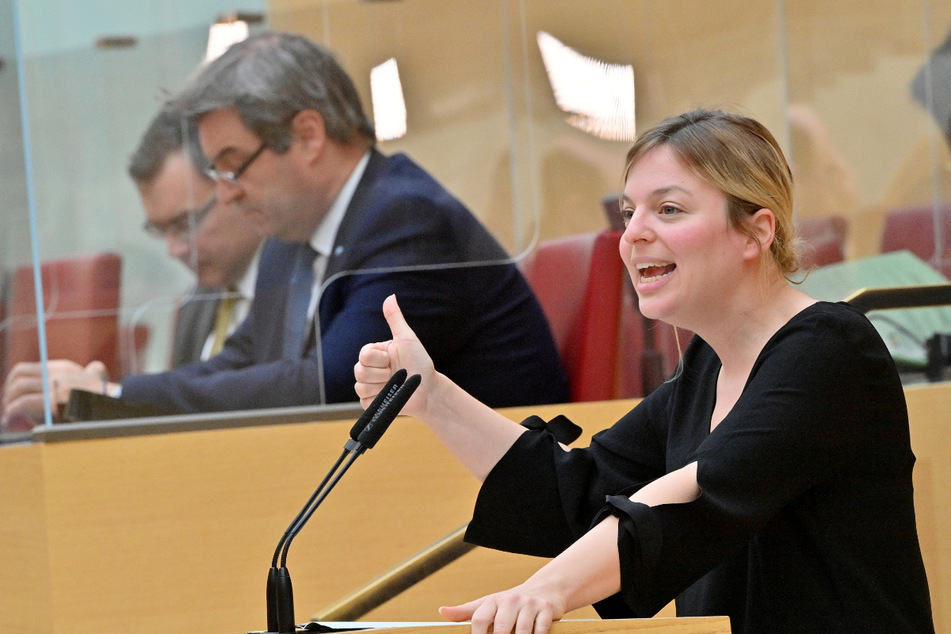 Katharina Schulze (35), Fraktionsvorsitzende Bündnis 90/Die Grünen im bayerischen Landtag, spricht in der Sondersitzung des Landtags zur Corona-Krise. Im Hintergrund ist Ministerpräsident Markus Söder zu sehen.