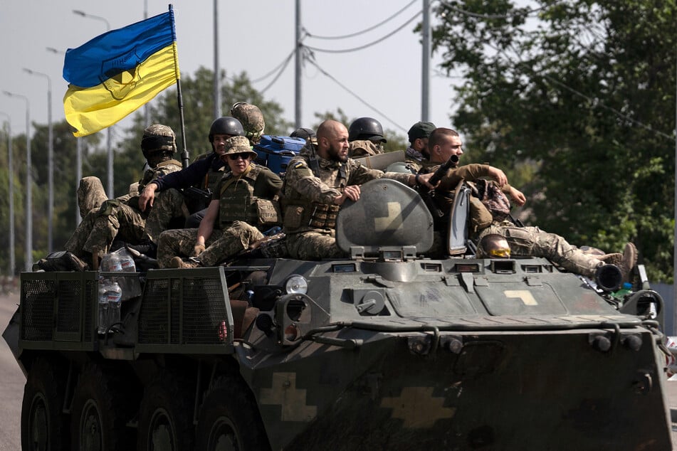Donezk: Ukrainische Soldaten fahren auf einem gepanzerten Fahrzeug auf einer Straße.