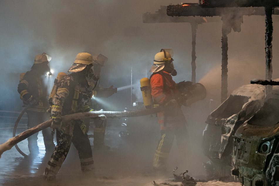 Feuerwehrleute kämpfen mit Schaum gegen das Feuer.