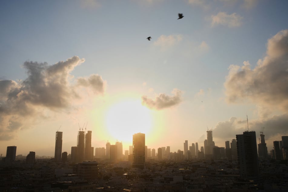 Die Sonne geht hinter der Stadtsilhouette von Tel Aviv auf.