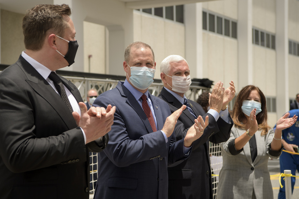 Unternehmer Elon Musk, NASA-Administrator Jim Bridenstine, Vizepräsident Mike Pence und Second Lady Karen Pence (v.l.n.r.) applaudieren, während die NASA-Astronauten Hurley und Behnken das Neil A. Armstrong Operations and Checkout Building auf ihrem Weg zu Pad 39-A im Kennedy Space Center in Cape Canaveral verlassen.