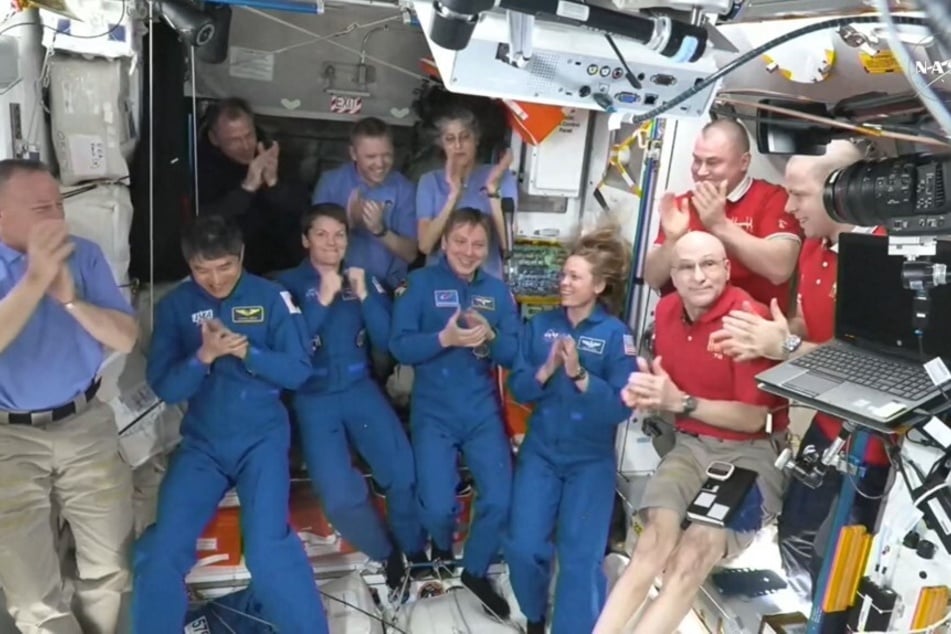 SpaceX Dragon Crew-10 members clap after entering the International Space Station flanked by NASA astronauts Butch Wilmore, Suni Williams, Nick Hague, and Don Pettit and Russian cosmonauts Aleksandr Gorbunov, Alexey Ochinin, and Ivan Vagner, on March 16, 2025.