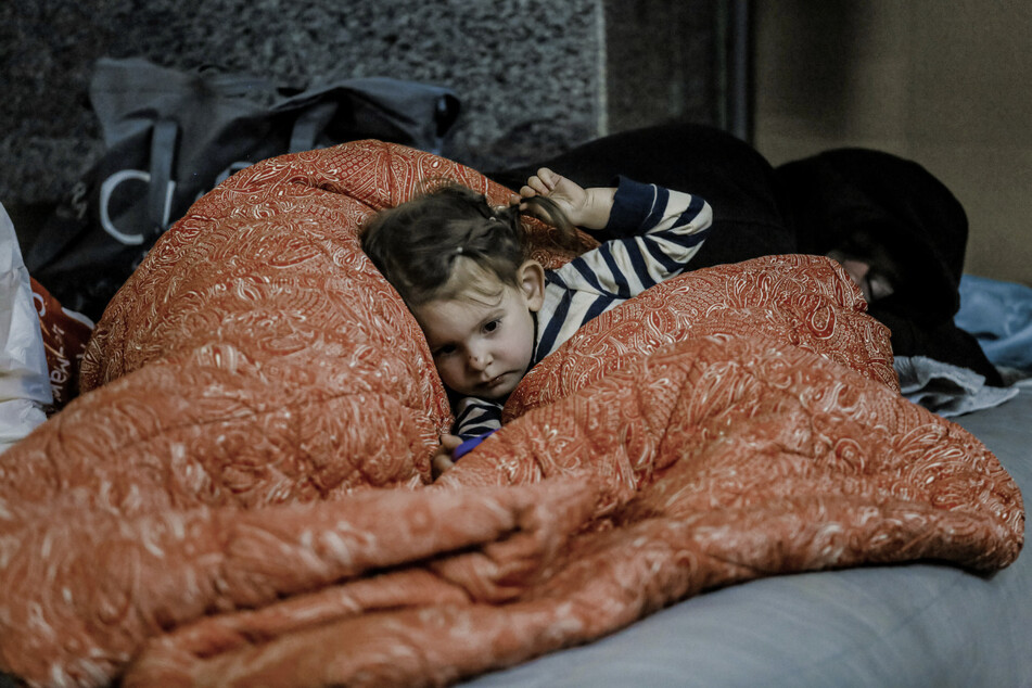 Ein kleines Mädchen liegt unter einer Decke in einer Metrostation in Charkiw. Der russische Krieg in der Ukraine treibt immer mehr Kinder in Armiut - auch in der EU!