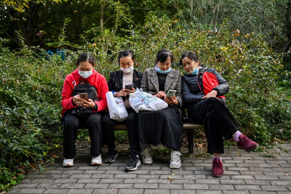 Vier Frauen sitzen auf einer Bank im Gongqing Forest Park im Shanghaier Stadtteil Yangpu.