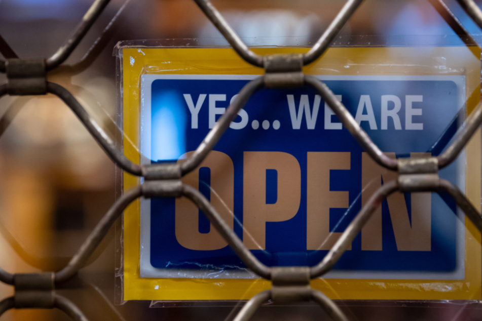 Ein Schild mit der Aufschrift "Yes...we are Open" ist kurz nach Ladenschluss an einem geschlossenen Geschäft zu sehen. Viele Kunden entscheiden sich für den Onlinehandel.