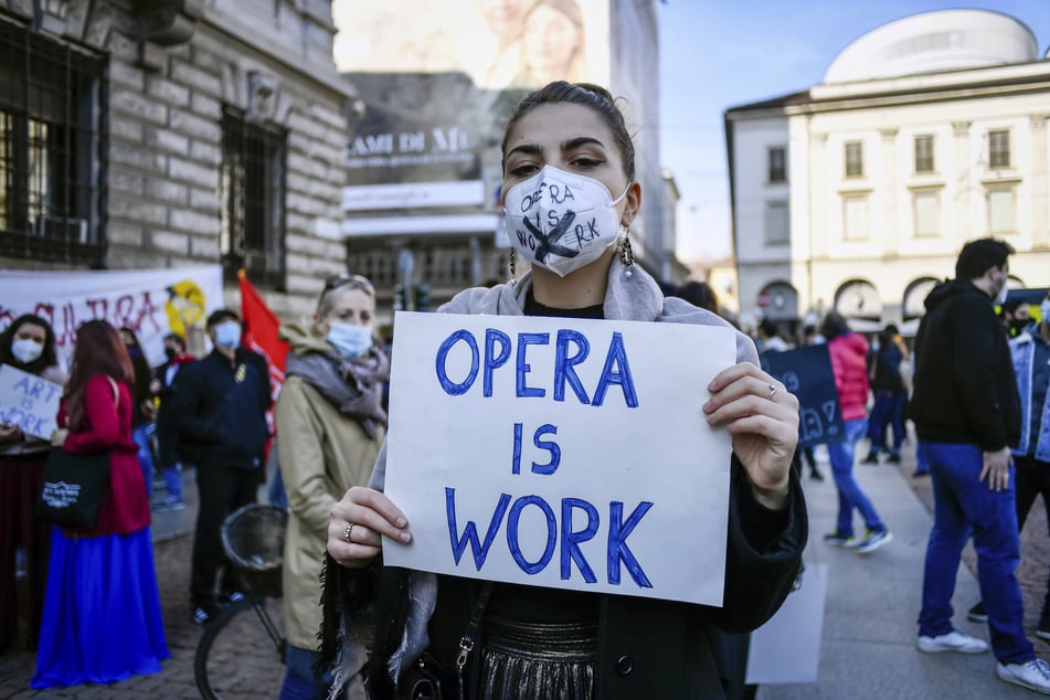 Eine Frau hält bei einer Demonstration gegen die Maßnahmen der italienischen Regierung zur Eindämmung der Corona-Pandemie ein Schild mit der Aufschrift "Opera is work" (zu deutsch: "Oper ist Arbeit") in den Händen.