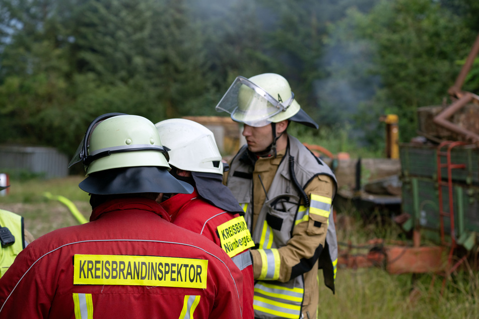 Feuerwehrleute stehen Anfang Juli am noch qualmenden Gartengrundstück in Altdorf.