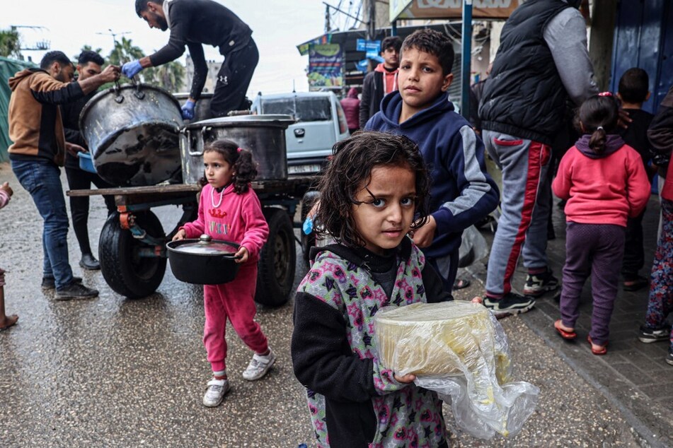 Displaced Palestinian children carry rations of red lentil soup as famine grips the Israeli-occupied territory of Gaza.