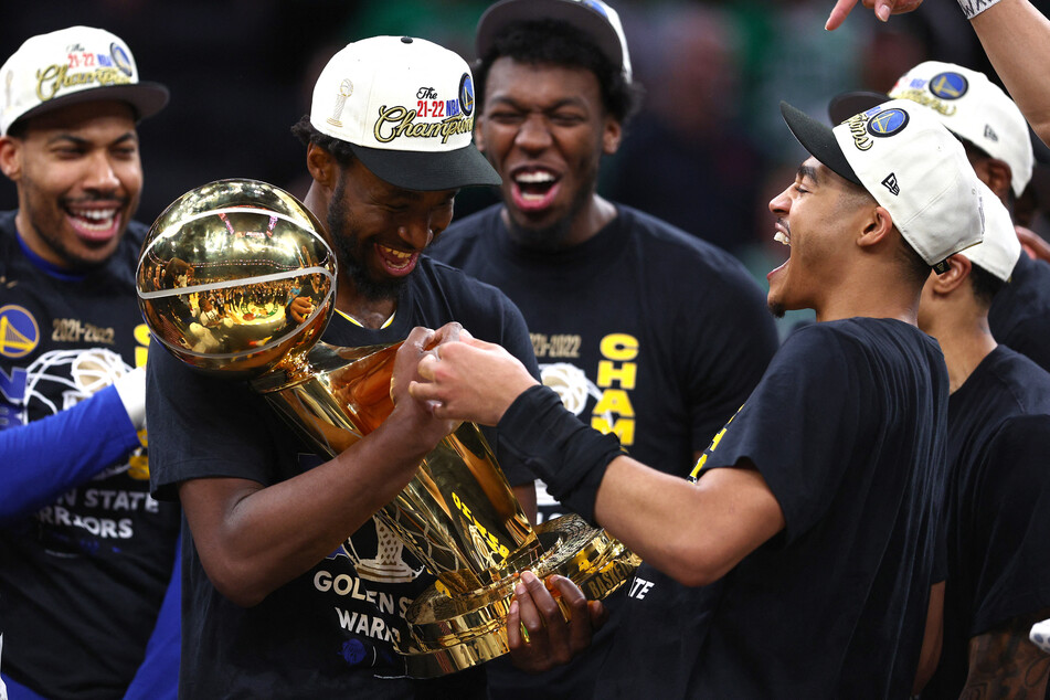 Andrew Wiggins (front l.) and Jordan Poole (front r.) celebrated with the Larry O'Brien Championship Trophy after defeating the Boston Celtics 103-90 in Game Six of the 2022 NBA Finals in June.