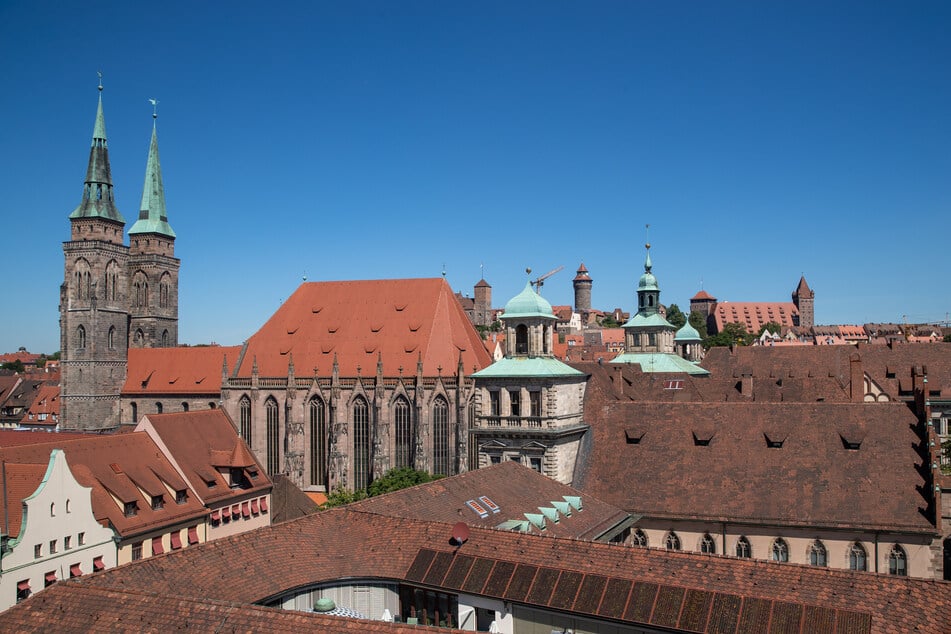 Blick auf die Kirche St. Sebald (l., Sebalduskirche) und die Kaiserburg (hinten Mitte) über die Dächer der Nürnberger Altstadt.
