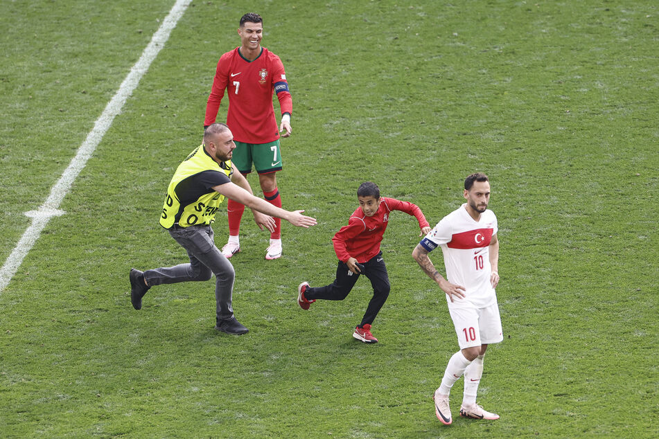 Der glückliche Junge flüchtet mit seinem Selfie im Kasten wieder vom Spielfeld. Ronaldo hat sichtlich Spaß.