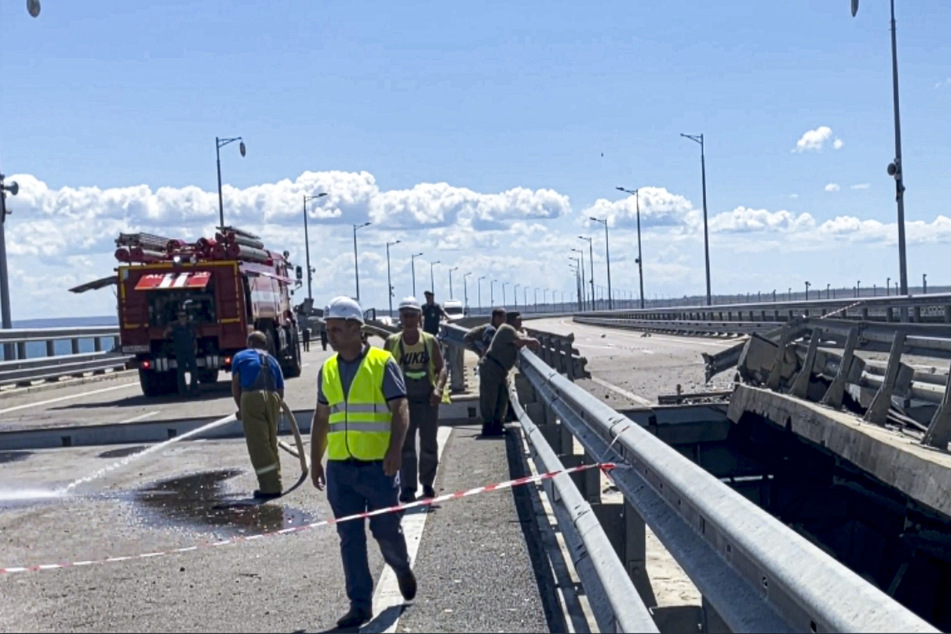 Mitarbeiter vom russischen Ermittlungskomitee an einem beschädigten Teil einer Autoverbindung der Krim-Brücke, die das russische Festland mit der Halbinsel Krim verbindet.