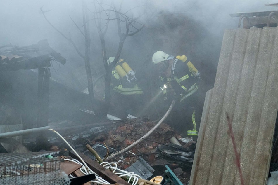 Kameraden der Feuerwehr kämpfen sich am Samstag durch die Überreste des Stalls, um die Flammen zu löschen.