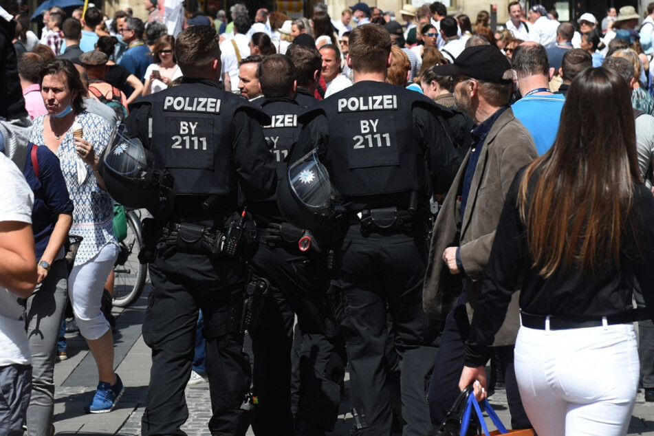 Polizisten gehen durch eine Menschenansammlung auf dem Marienplatz.