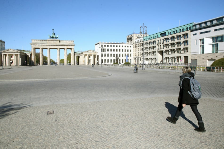 Eine junge Frau geht über den fast menschenleeren Pariser Platz vor dem Brandenburger Tor.