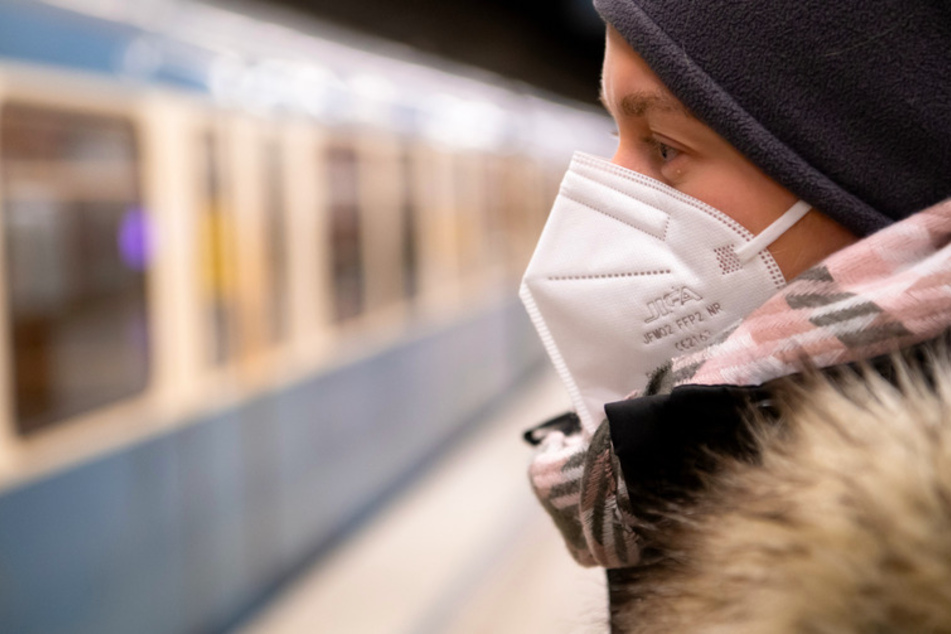 Ein Frau mit FFP2-Maske wartet in einer U-Bahnstation auf die Bahn.