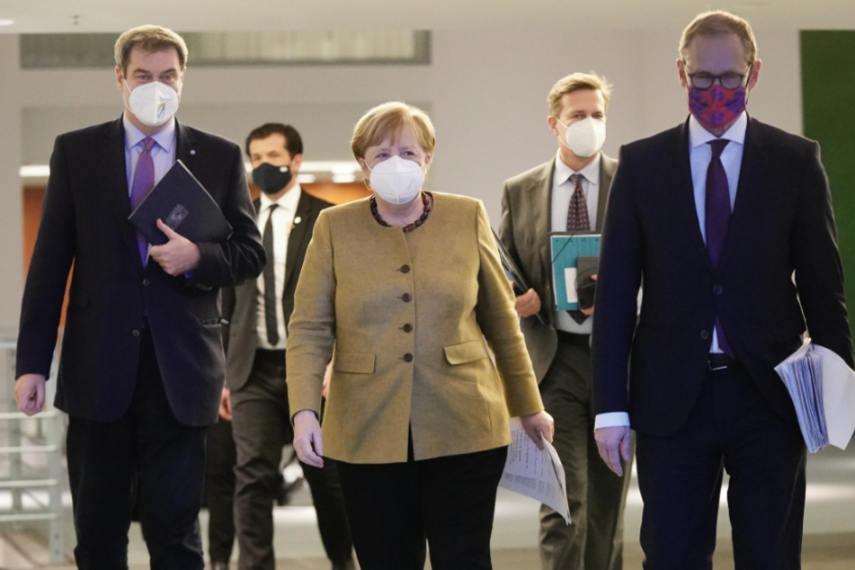 Bundeskanzlerin Angela Merkel (CDU), kommt neben Markus Söder (CSU, l), Ministerpräsident von Bayern und CSU-Vorsitzender, sowie Michael Müller (SPD, r), Regierender Bürgermeister von Berlin, zu der Pressekonferenz nach den Beratungen von Bund und Ländern über weitere Corona-Maßnahmen.