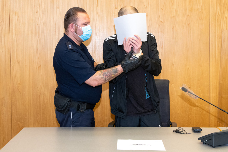 Ulm, 25. August: Ein Justizwachmeister führt den Angeklagten. Dieser versteckt sein Gesicht.