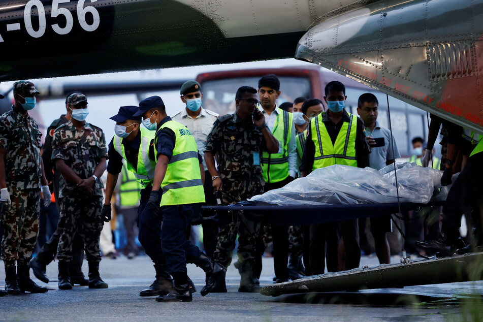 Members of the Nepalese Army load the body of a victim onto a plane.